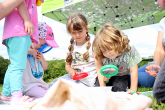 Children with magnifying glasses looking for bugs by Lauren Roberts