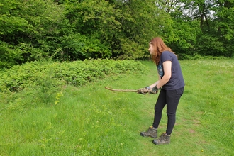 Woman with a stick to bash bracken by Iain Turbin