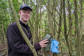 Trainee Charlie checking a dormouse box at Monkwood