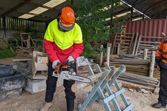 Patrick cutting a log with a chainsaw