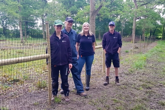 Four conservation trainees stood in front of deer fencing