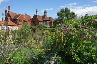 A flower-filled garden with a red brick house in the background