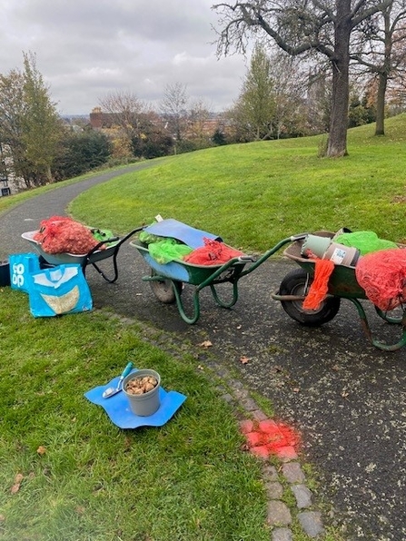 Three wheelbarrows loaded with kit on a path through an urban park